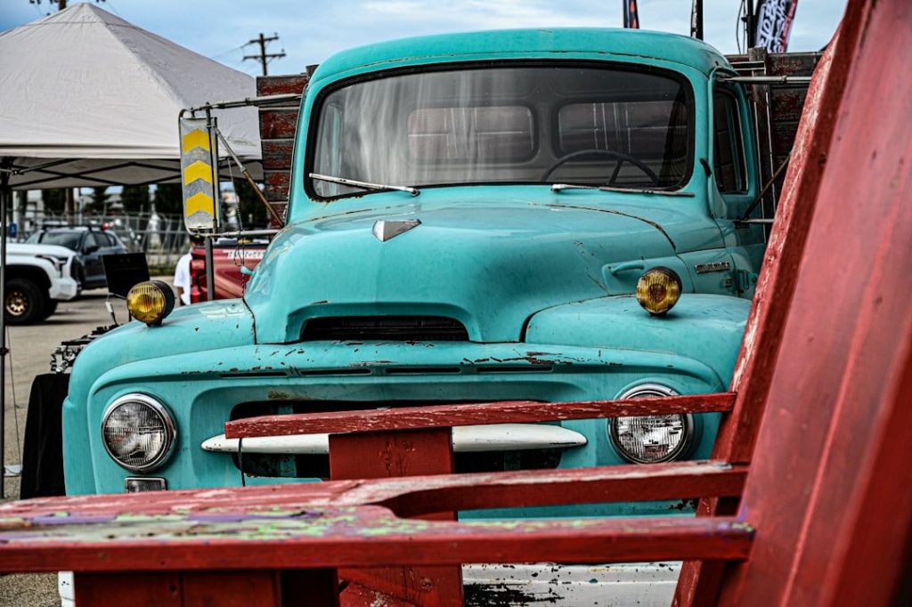 Frontvy av en klassisk turkos begagnad lastbil på en bilutställning.