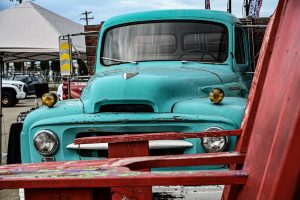 Frontvy av en klassisk turkos begagnad lastbil på en bilutställning.