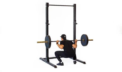 Man utför knäböj med skivstång i en robust träningsställning.